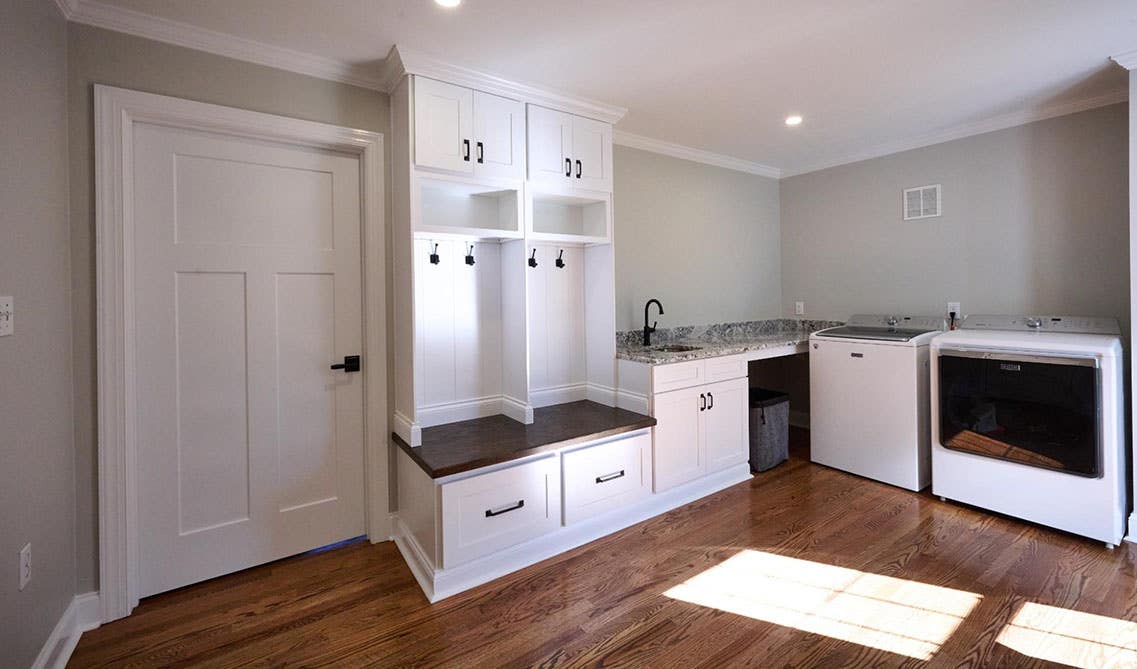 Laundry Room with washer, dryer, siting bench, hooks for cloths, marble countertop and black hardware