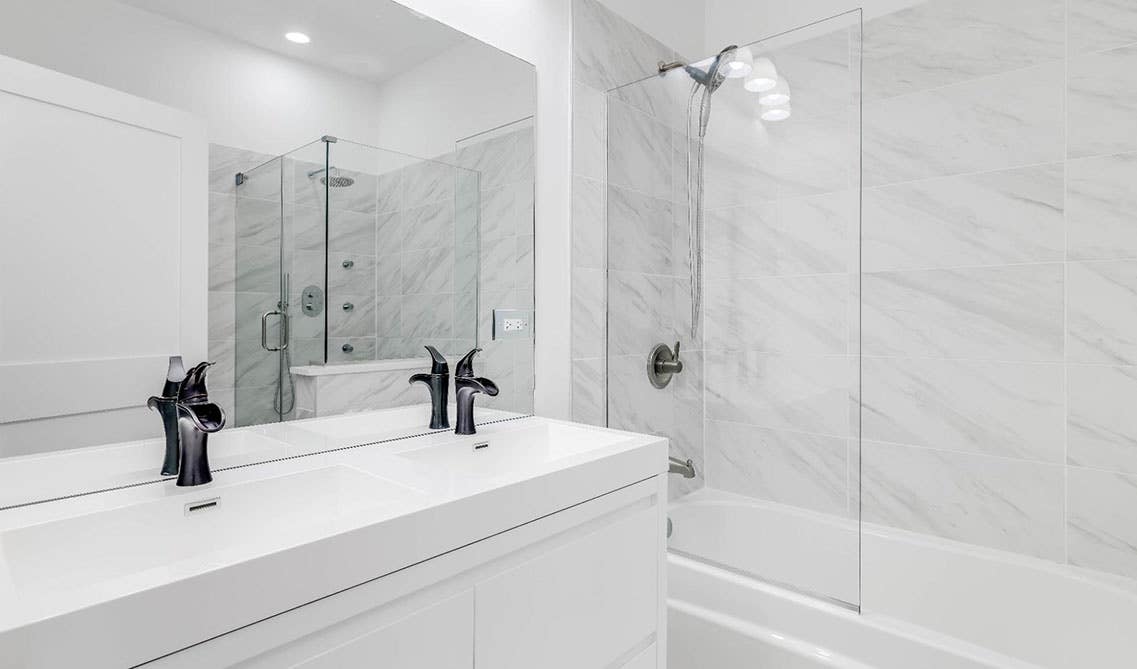 All white bathroom design features flat door vanity with double sink, and separate shower area