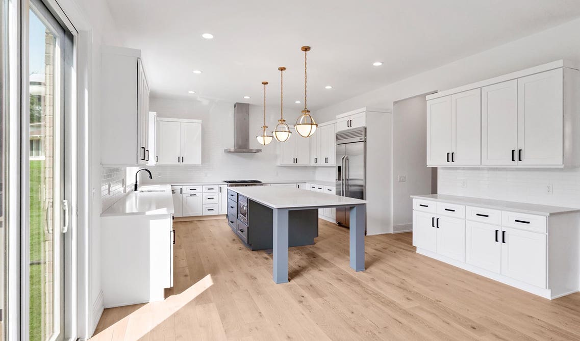 White stylish kitchen design with large island, pendent lights, and matt black fixtures 