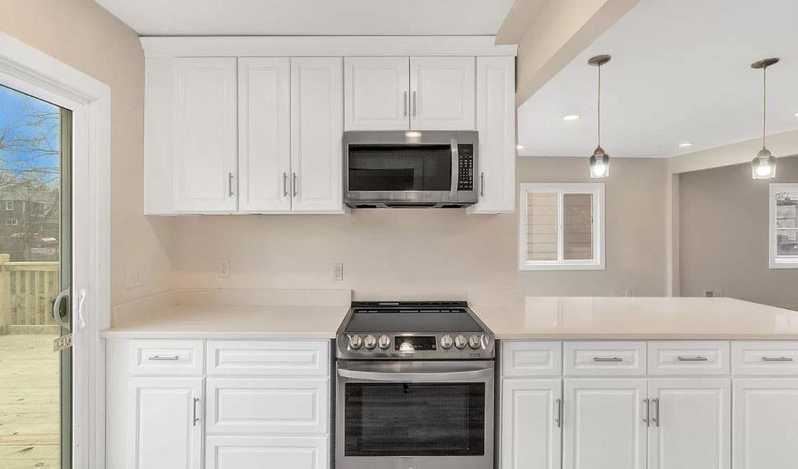 Single wall kitchen with white cabinets with beige countertop and ceiling lights