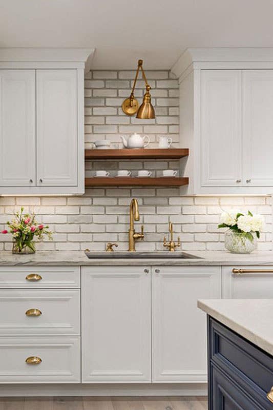 Whitewashed Brick Backsplash with brown open shelving and white cabinets