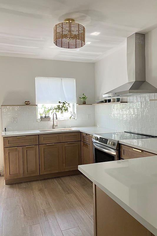 Craftsman natural shaker cabinets paired with white countertop, white subway tiles backlash and stainless appliances