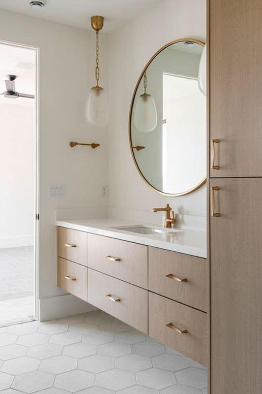 Wooden floating vanities with gold hardware and marble countertop