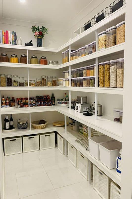 L Shape Walk In Pantry with White floating Shelves stored with containers and baskets