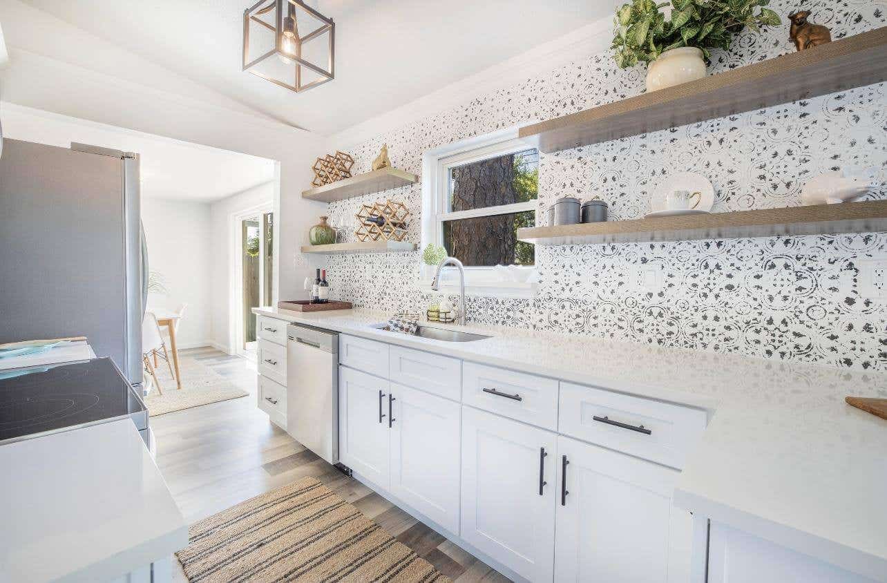 Kitchen with white cabinets, marble countertop, open shelves, and pattern tile backsplash