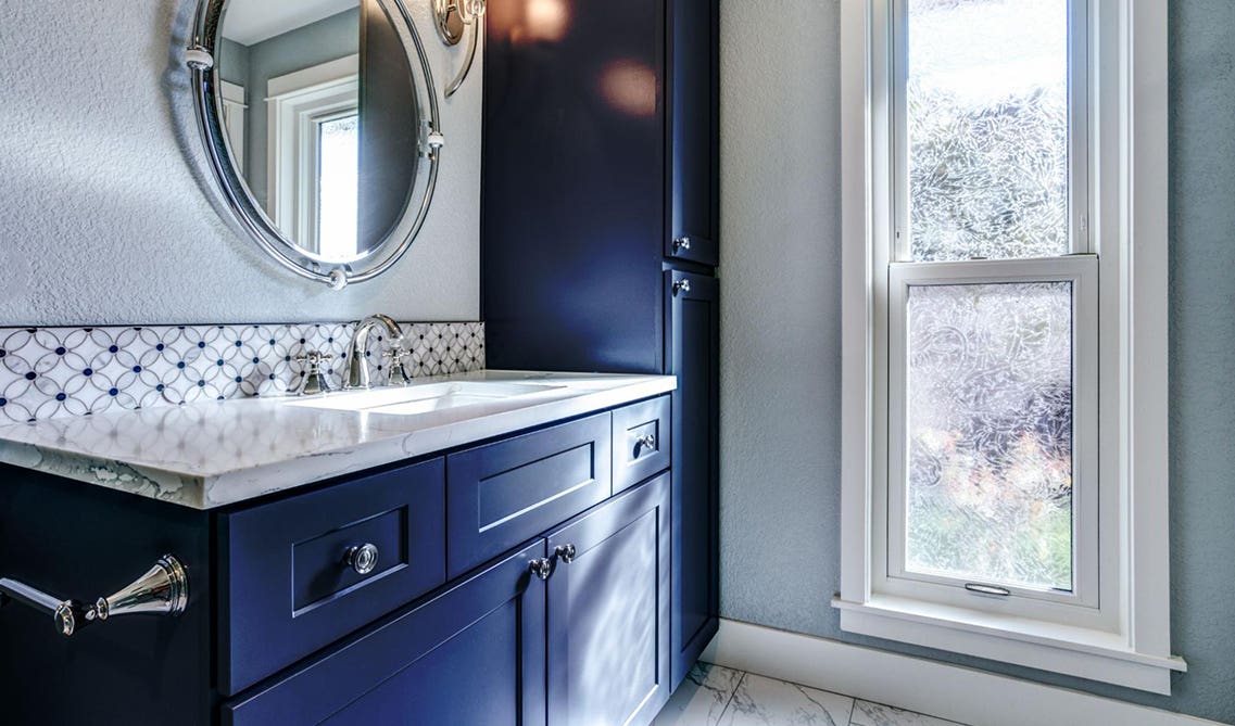 Navy blue bathroom vanity with white countertop and mirror