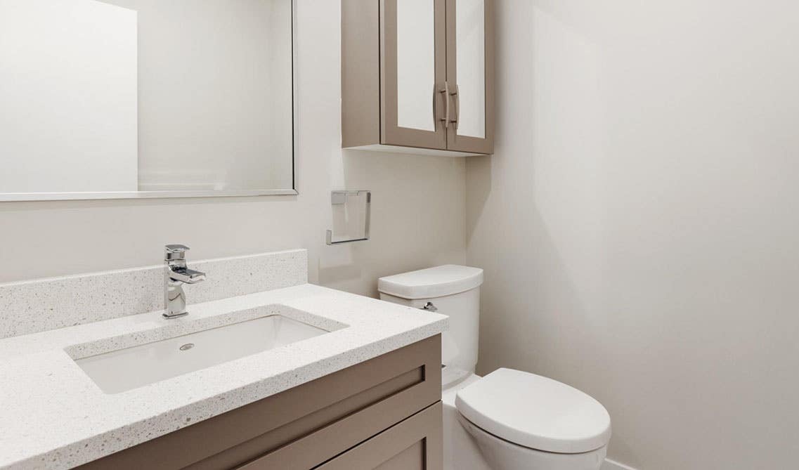 Sleek bathroom design with brown vanity with sink, Quartz Tops, and big square mirror