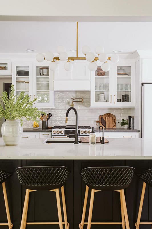 White shaker cabinets with glass door, black countertop, subway tile backsplash and gold accent