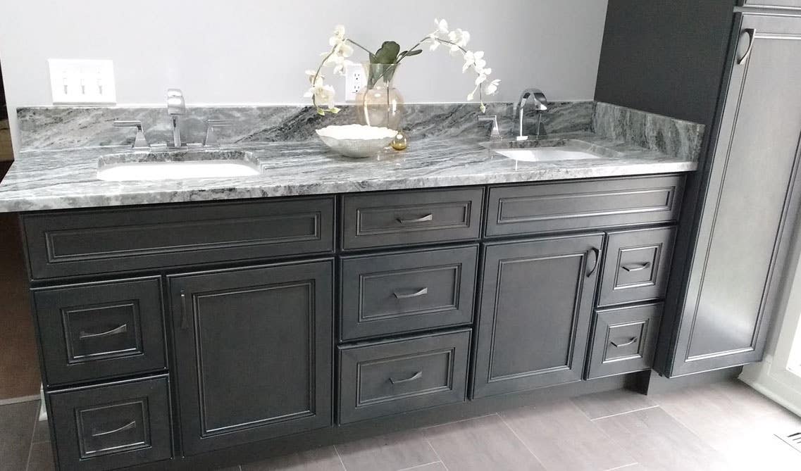 stylish black bathroom vanity with marble countertop, and double sink with steel fixture 