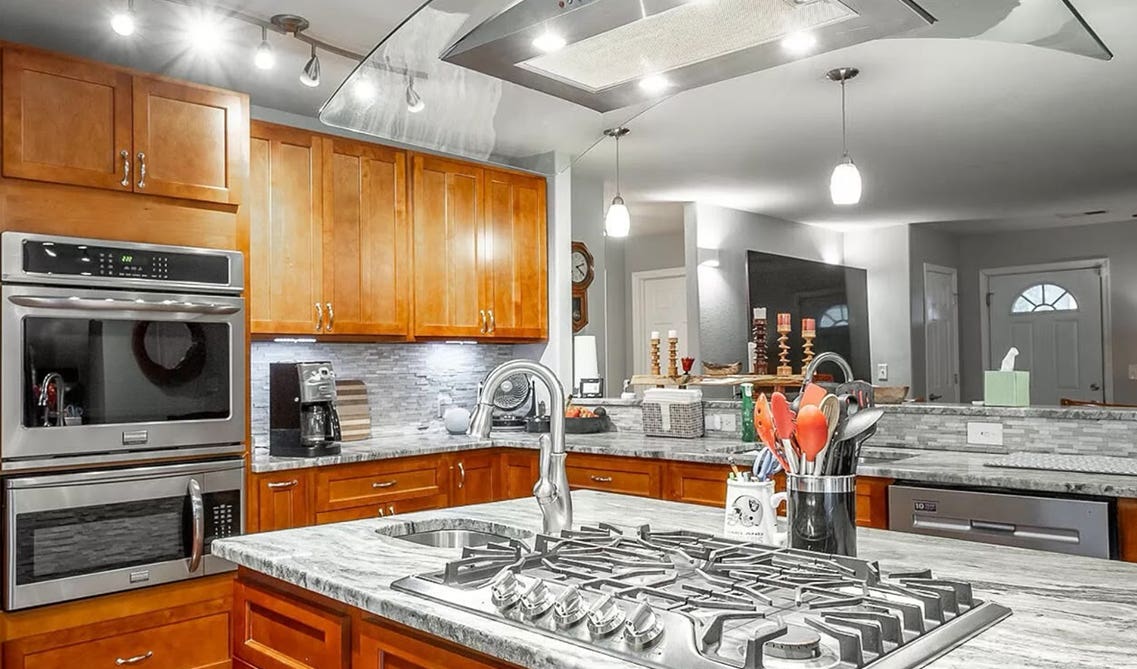 Cozy cottage kitchen with brown cabinets, stainless steel appliances and quartz countertop 