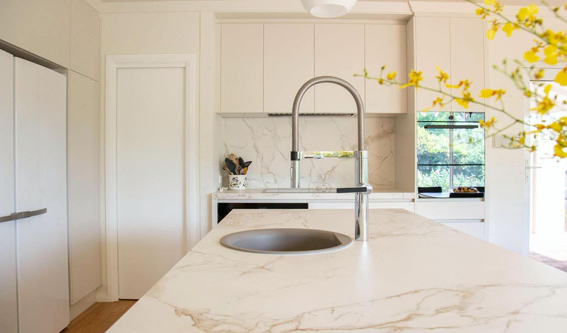 Modern cream kitchen cabinets with marble backsplash and countertop, 