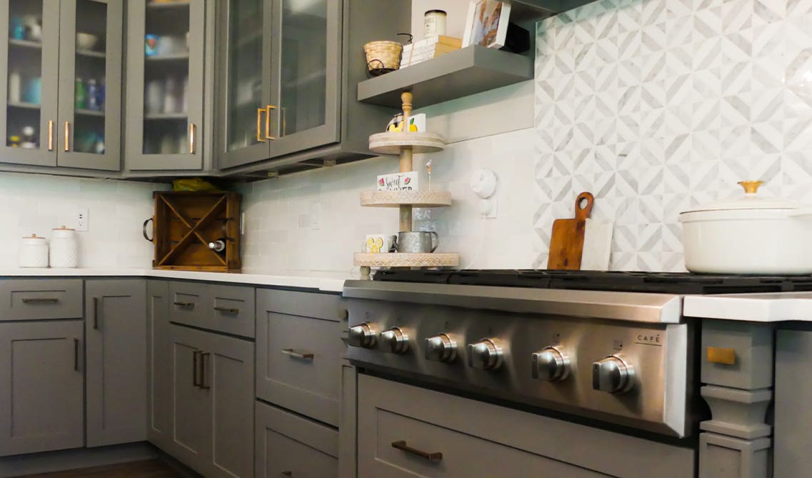 Elegant kitchen design with gray cabinets with stainless steel Stove, white backsplash and open shelving.