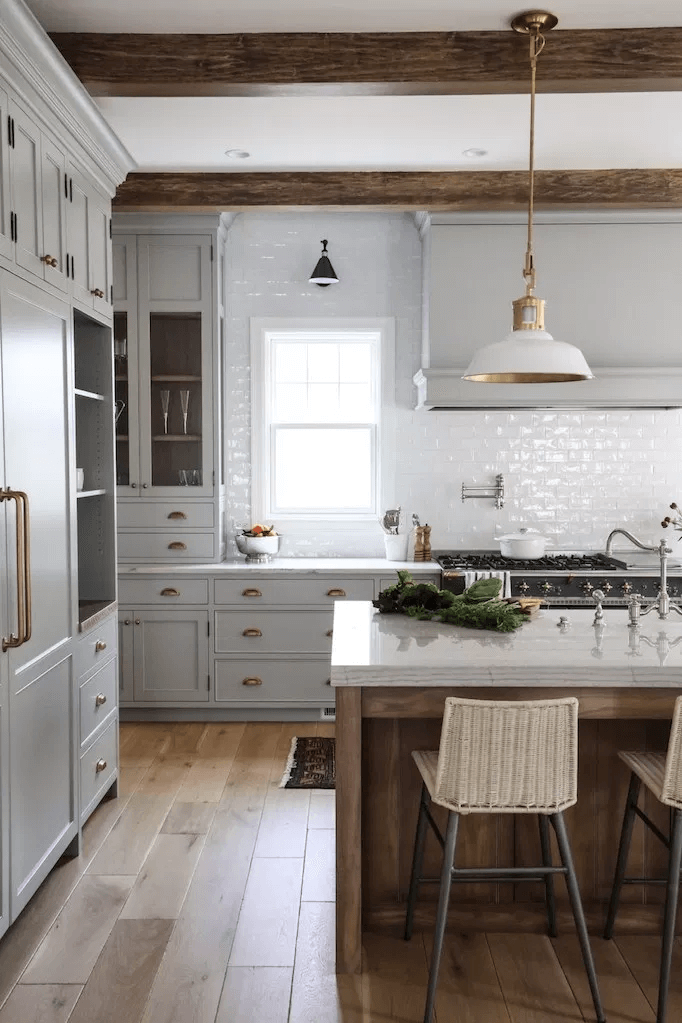 large bright modern farmhouse kitchen with light gray inset cabinets vintage hardware and glossy white backsplash 