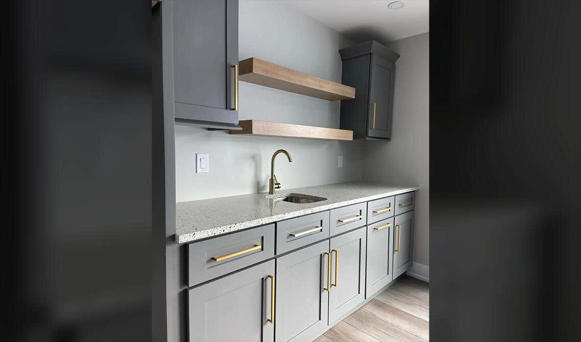 Gray bathroom cabinets with gold hardware and floating shelves