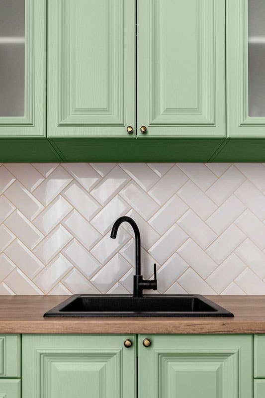 green cabinets with wooden countertop and black fixtures 