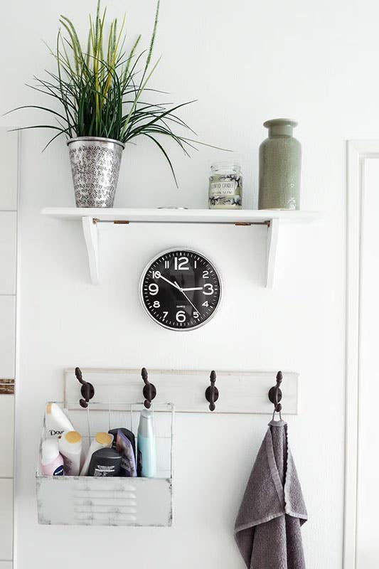 bathroom shelves with green plan, wall clock, hooks for towel