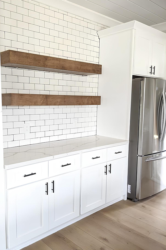 Wooden floating shelves paired with white cabinets and subway backsplash 