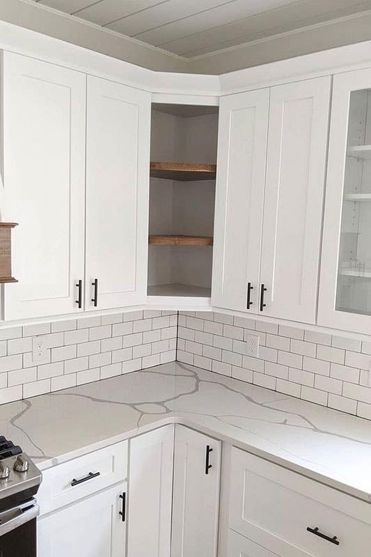 Small kitchen idea- corner open shelves and white cabinets with black pulls, subway tile backsplash and marble countertop