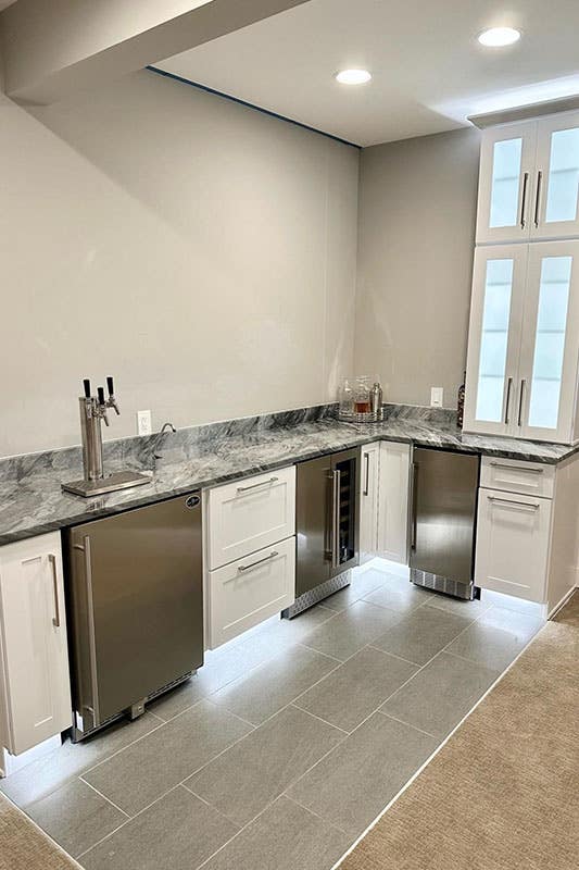 kitchenette with white cabinets, marble countertop and stainless steel appliances