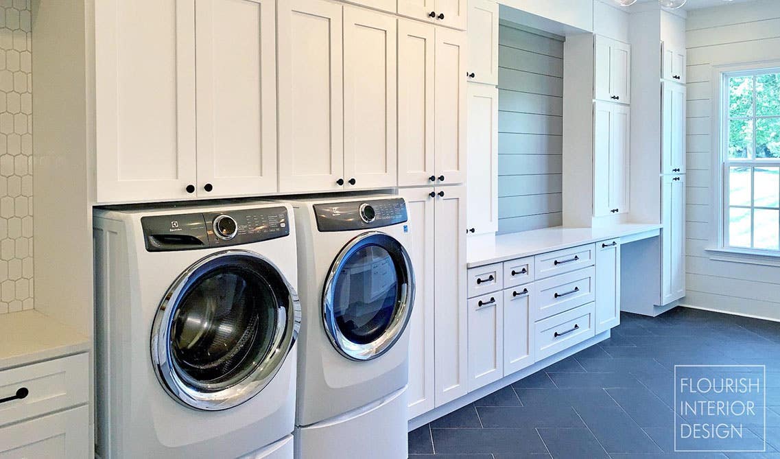 Laundry room with white storage cabinets, Tile Flooring, 6 Head Chandelier, sitting bench