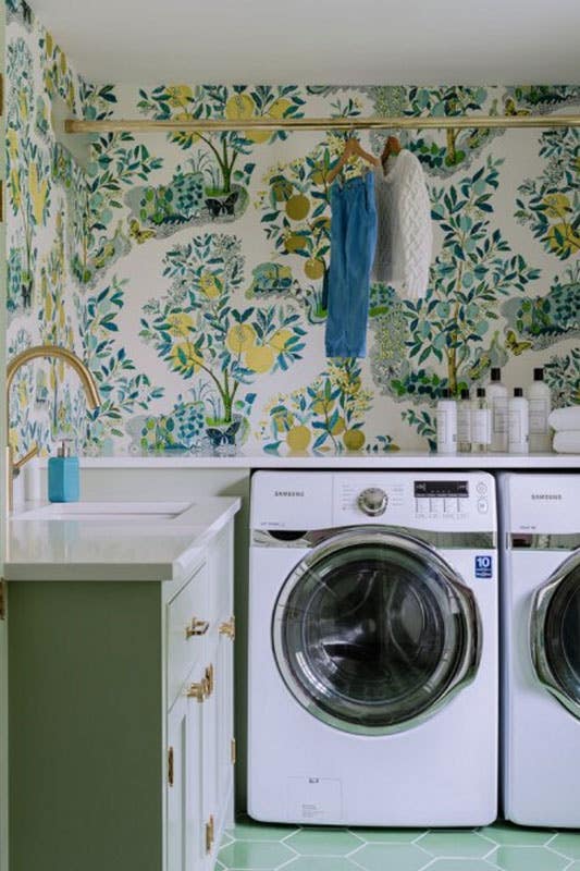 laundry room with green cabinets, gold hardware, floral wallpaper, and washer and dryer