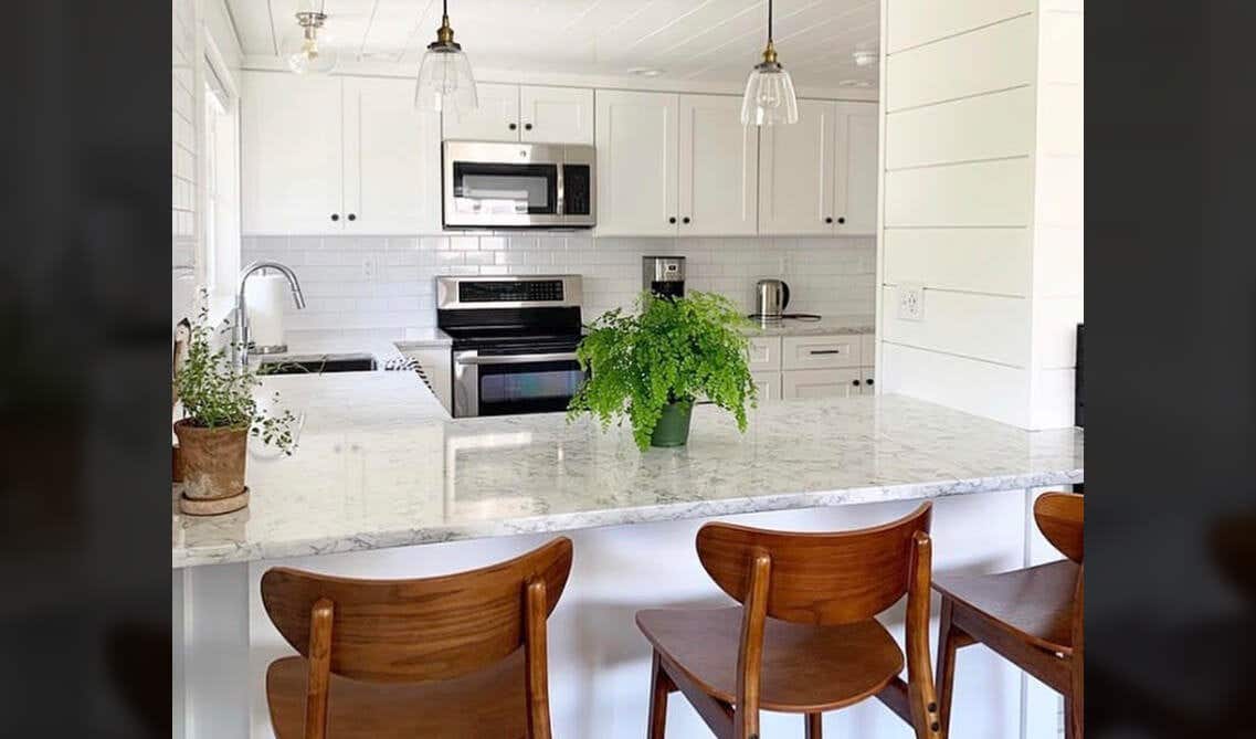 All White Kitchen Design with Cabinets, island, subway tiles, wooden chairs and ceiling lights 