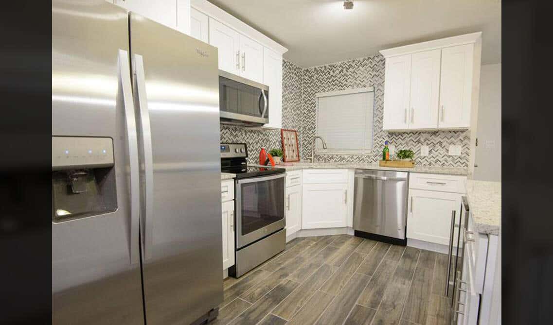 White cabinets kitchen with Herringbone Pattern subway tile, stainless steel appliances and SPC flooring 