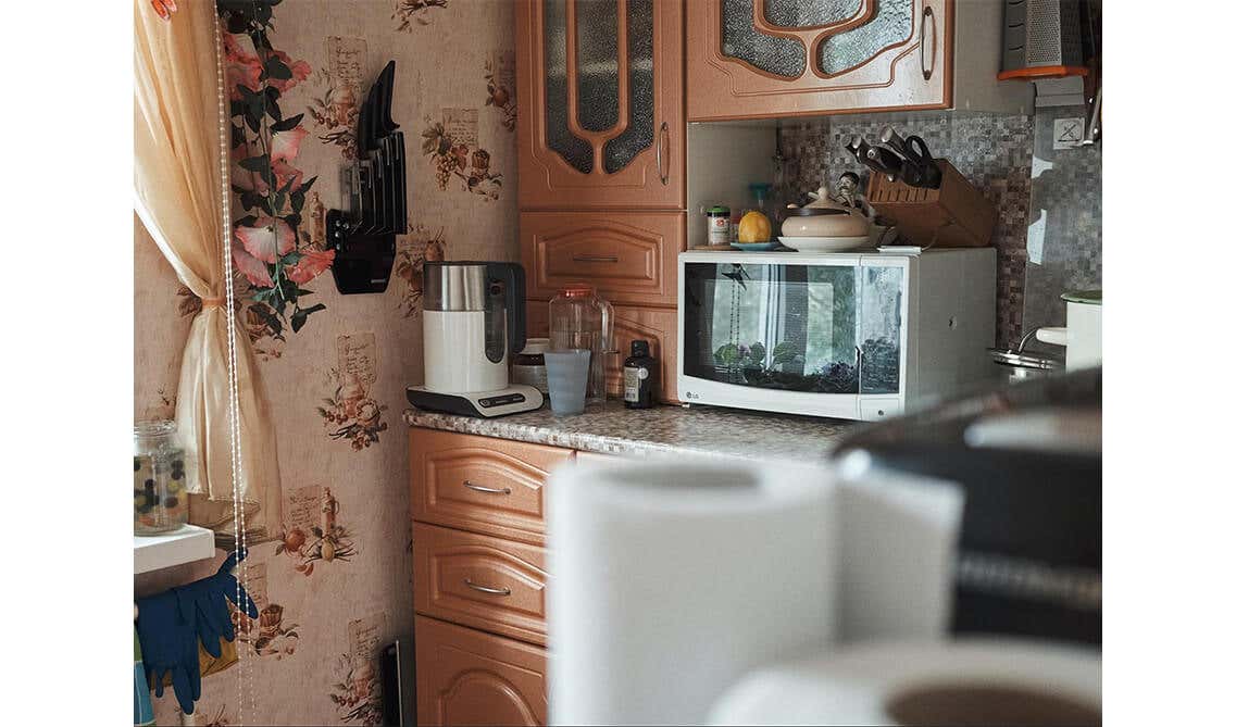 kitchen with brown cabinets with marble countertop, microwave, and kitchen utensils 