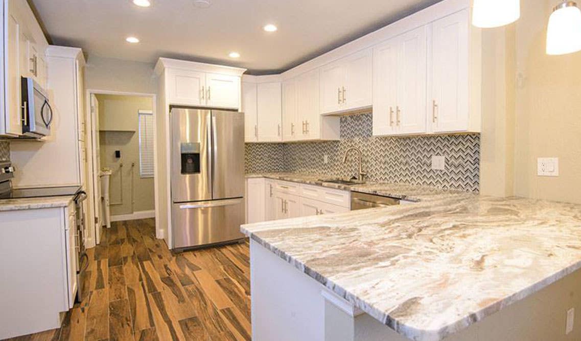 modern kitchen design with white cabinets, pattern backsplash tiles, stainless steel appliances and spc flooring 