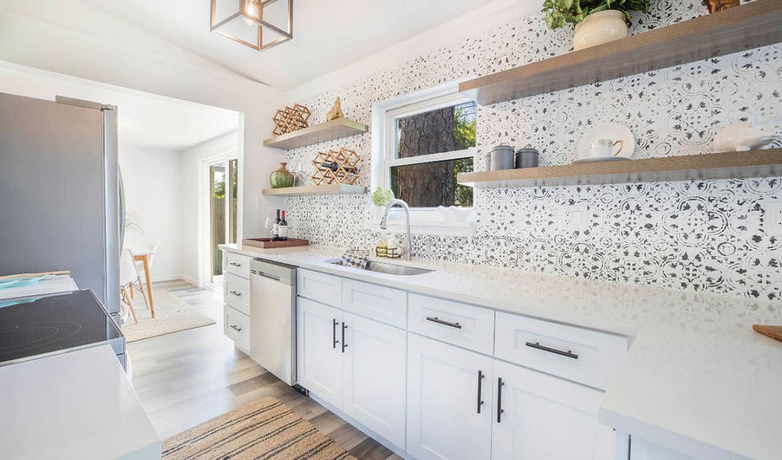 White kitchen cabinets with pattern backlashes, white countertop and floating shelves 