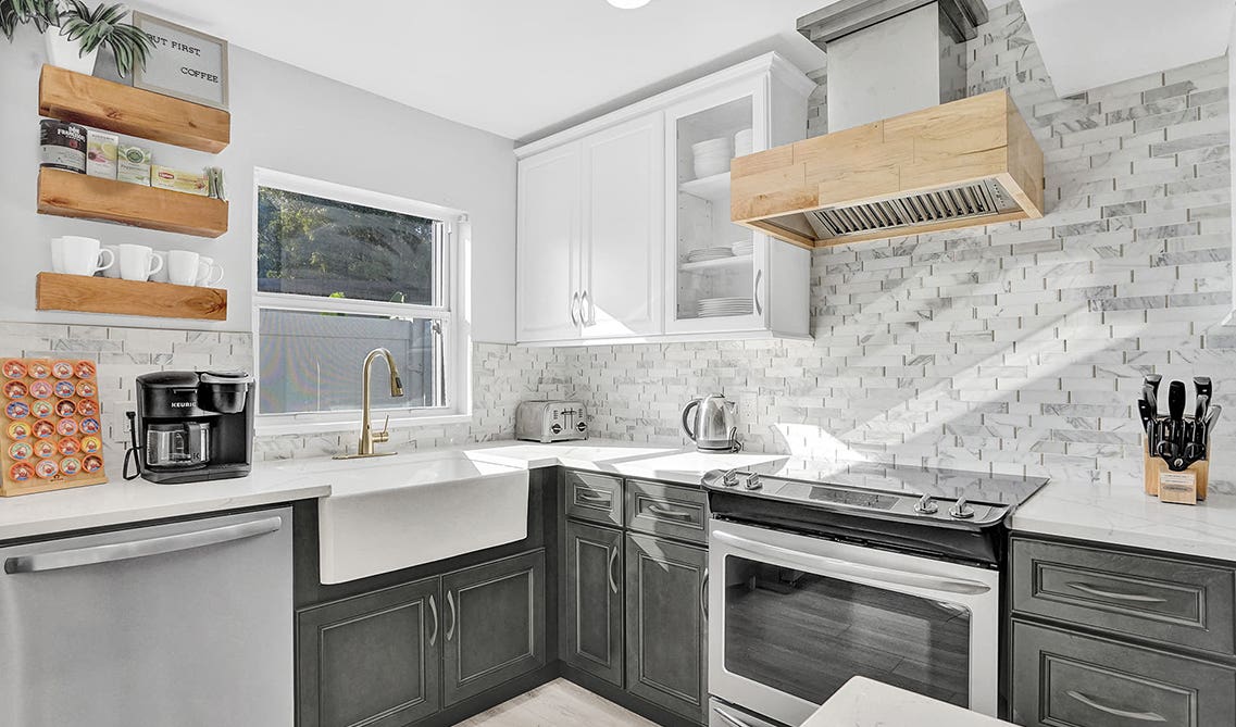 two-toned farmhouse kitchen design with floating selves and brick style backsplashes 