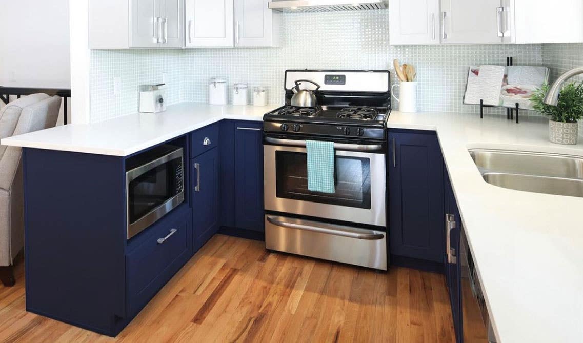 two tone blue and white cabinets with white countertop, stainless steel appliances and spc flooring, 