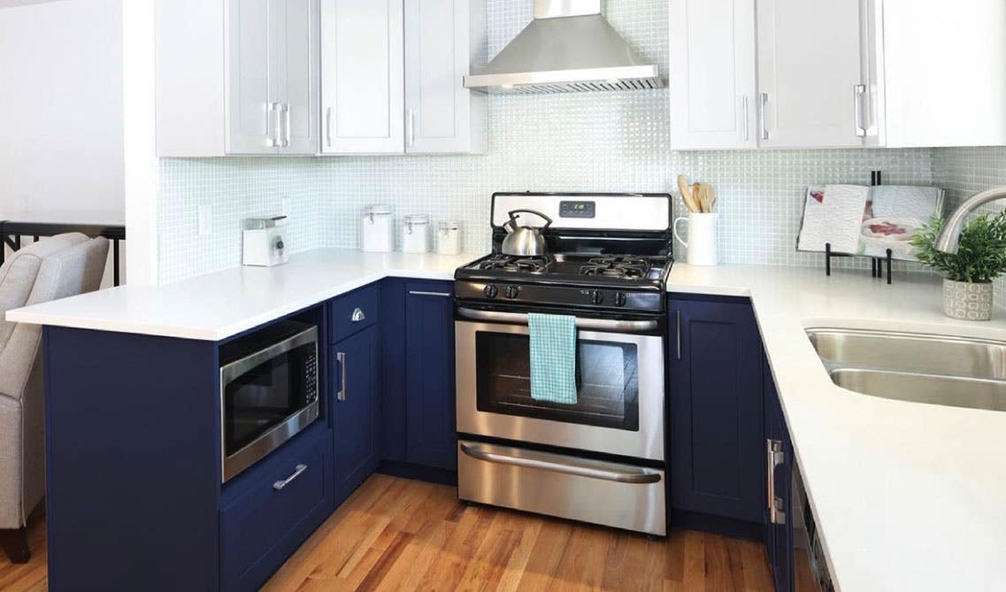 two toned navy blue and white kitchen cabinets with stainless steel appliances 