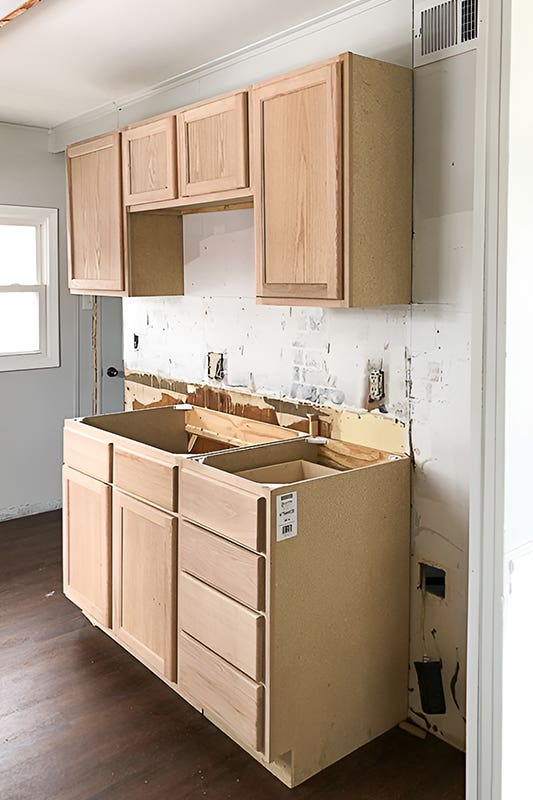 Unfinished kitchen cabinets paired with brown floor tile