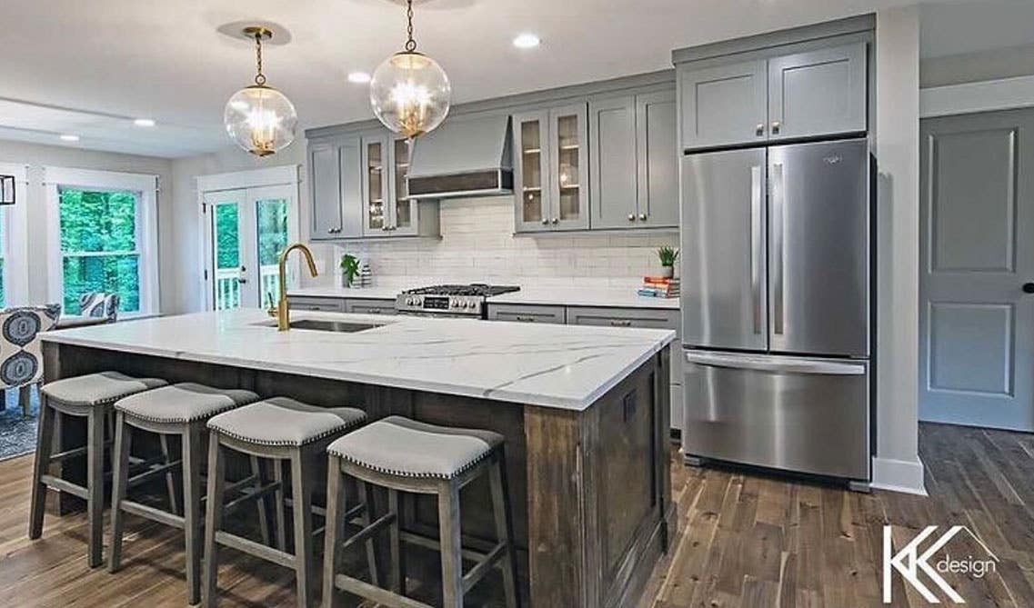 One wall kitchen with gray shaker cabinets, Large island with sink, 4 stool chair, marble countertop, beautiful round pendant light, wooden flooring