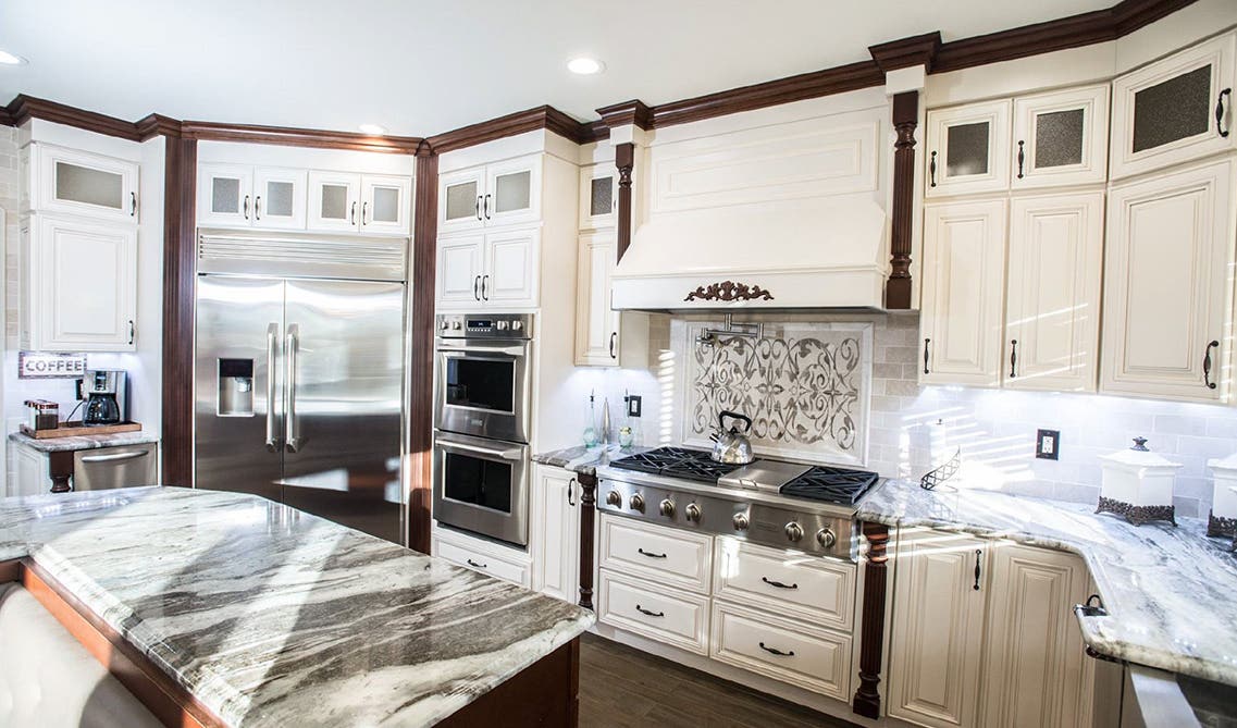 Traditional Kitchen with cream cabinets, marble countertops, and stainless steel appliances