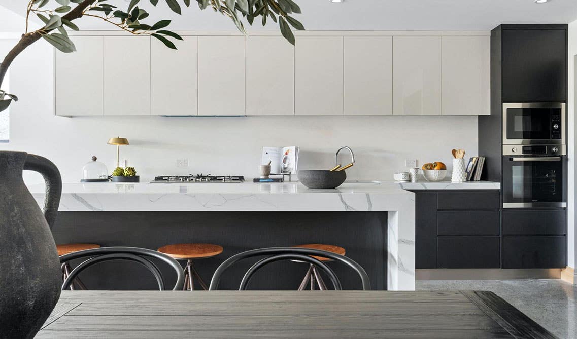 Stylish one wall kitchen with flat door white and black cabinets, island with waterfall countertop