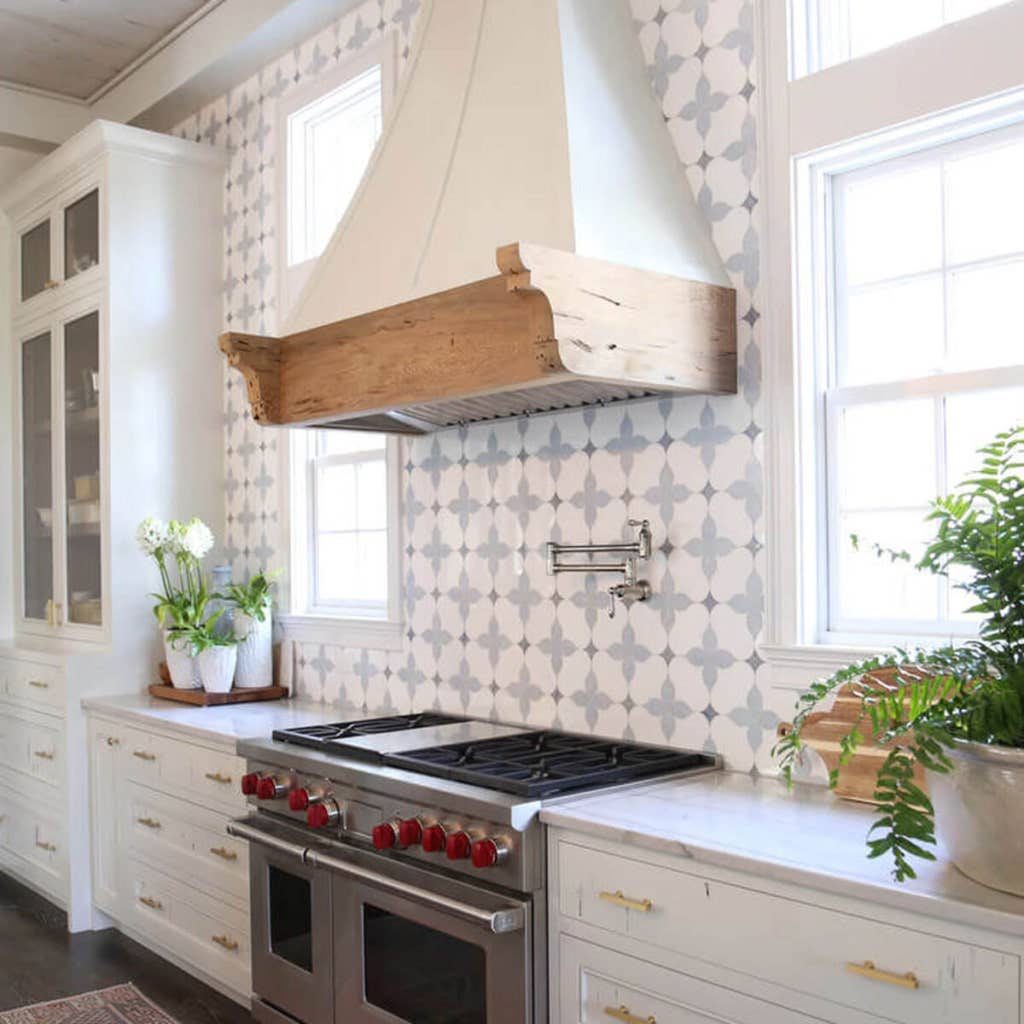 White kitchen with glossy Victorian patterned tile backsplash and wooden rangehood 