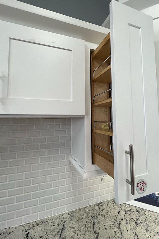 white Pull-out cabinet organizers with the stainless steel pulls and white subway tiles