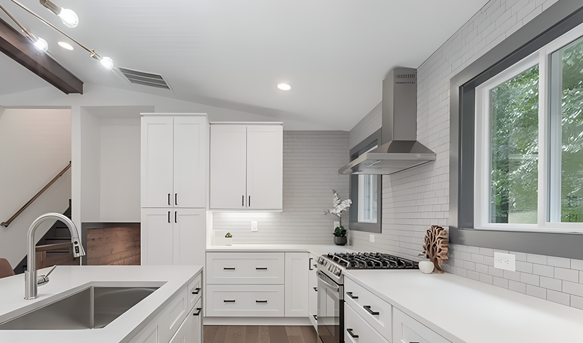white and gray kitchen paired with stainless steel appliances, subway title backsplash and wood flooring 