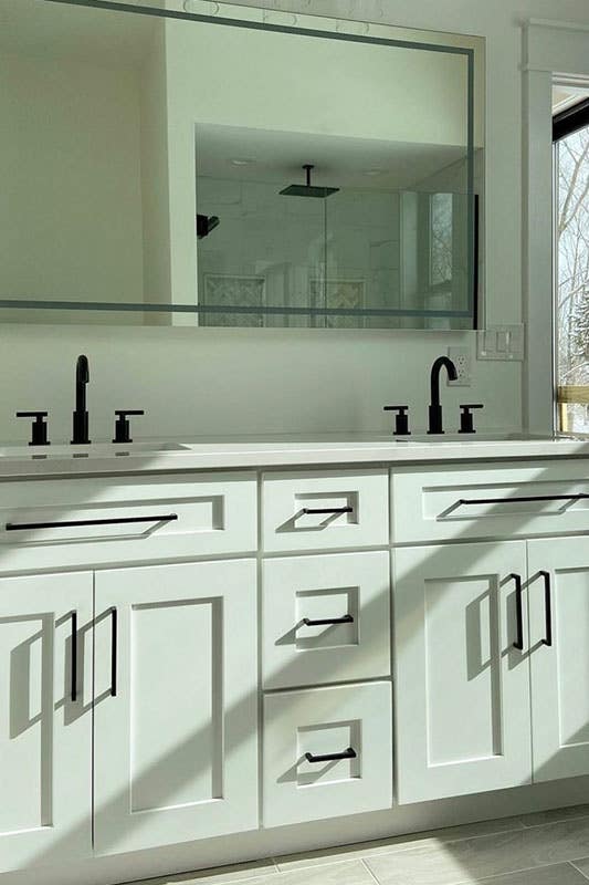 white bathroom vanity with black fixtures and mirror 