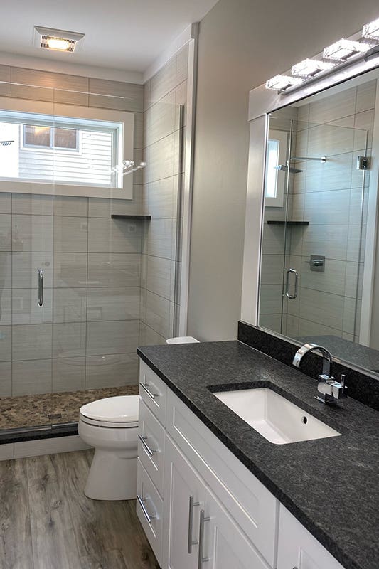 white bathroom vanity paired with black countertop and silver hardware