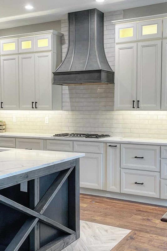 white cabinets with black hardware, white subway backspace tiles, grey wood hood and island 