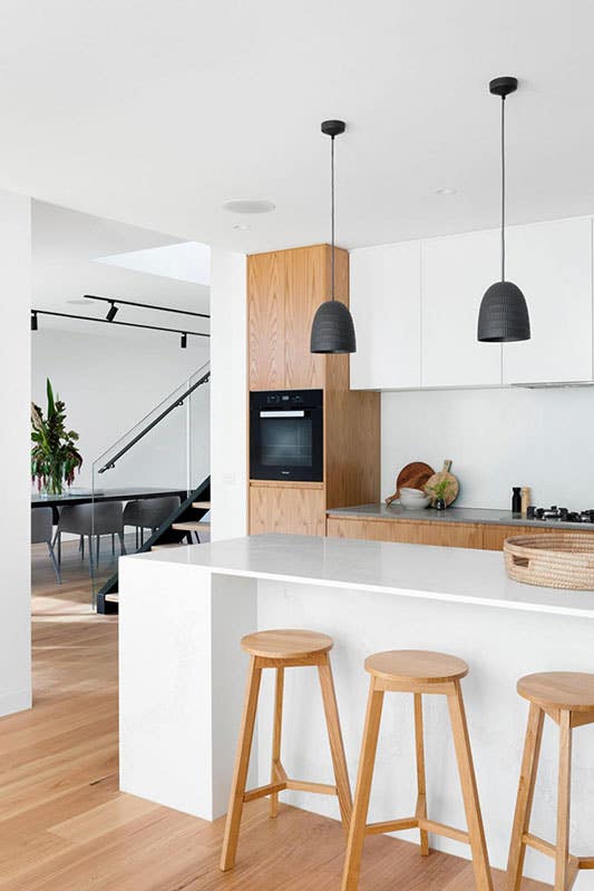 Kitchen design with oak cabinets, large island with three stool chair and stylish pendent light