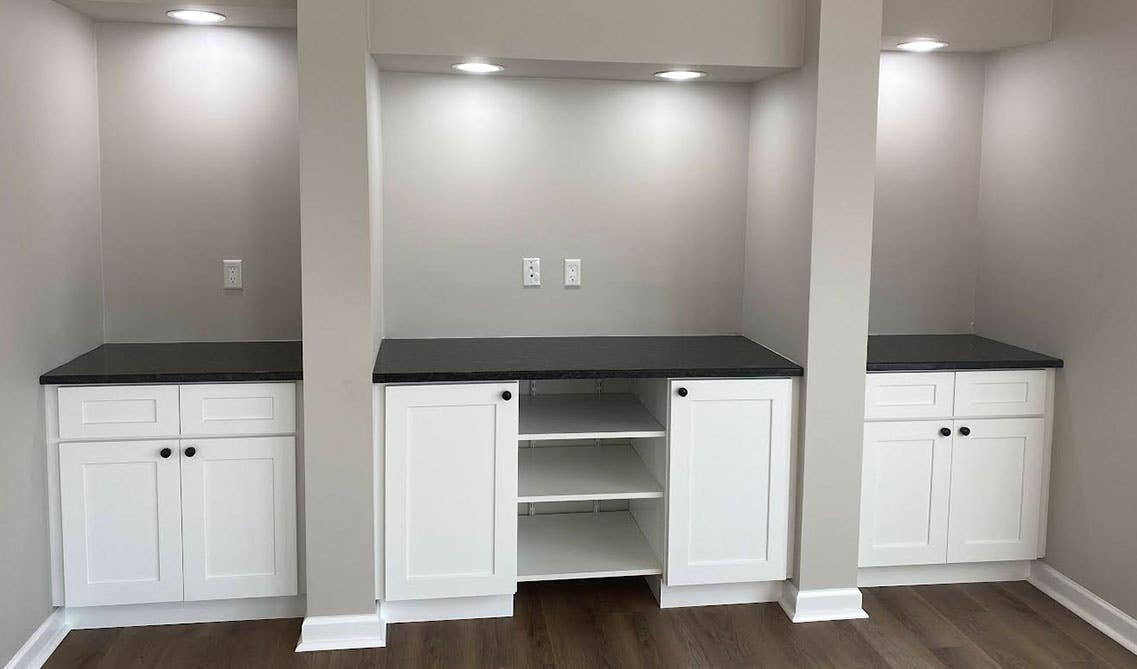 Living area with white storage cabinets and black countertops 