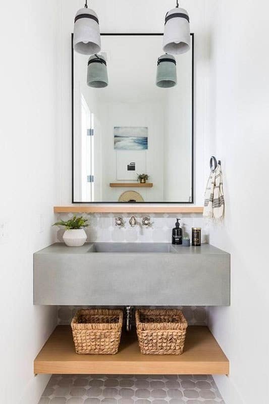 wooden shelf with concrete countertop and large mirror 